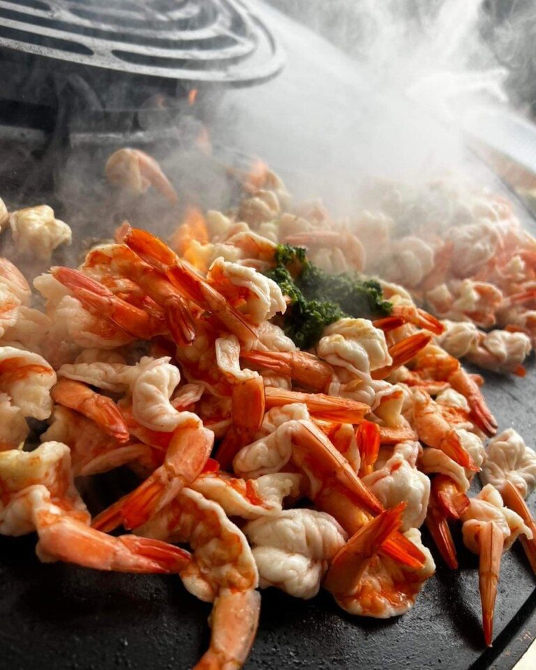 Crevettes grillées sur la plancha, fumée au-dessus de la grille