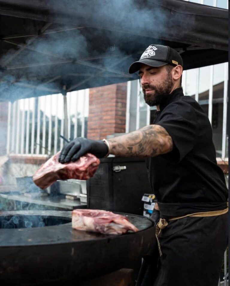Cuisinier tenant une pièce de bœuf au-dessus du braséro