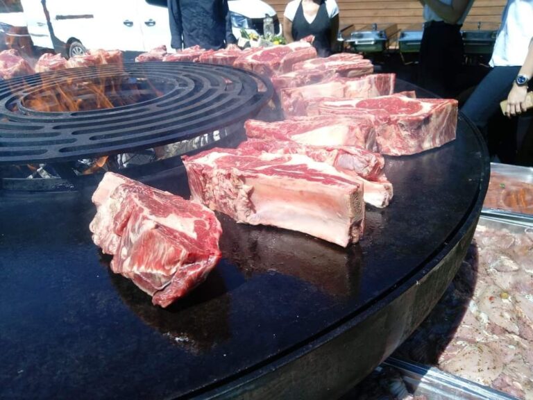 Côtes de bœuf crues sur la grande plancha ronde d'un braséro de 150