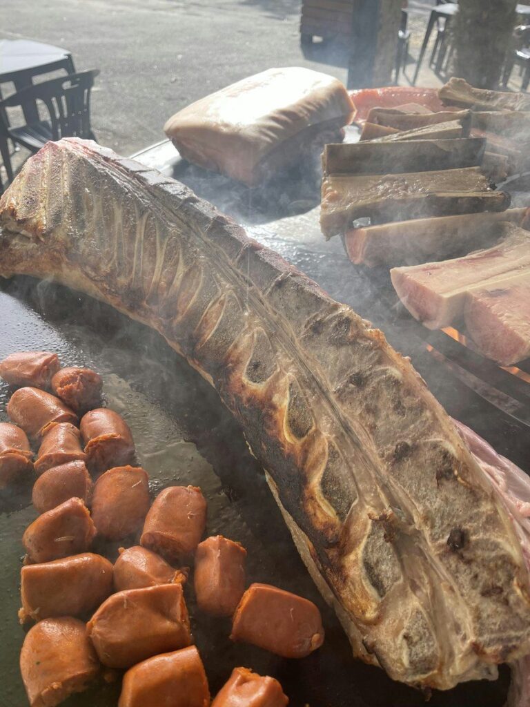 Grande pièce de bœuf sur l'os grillée sur la plancha, saucisses coupées au premier plan