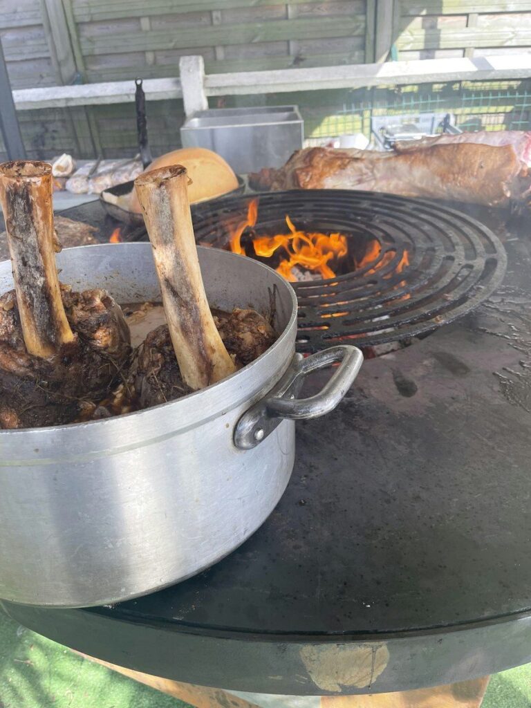 Marmite d'os posée sur la plancha à côté du foyer en flammes