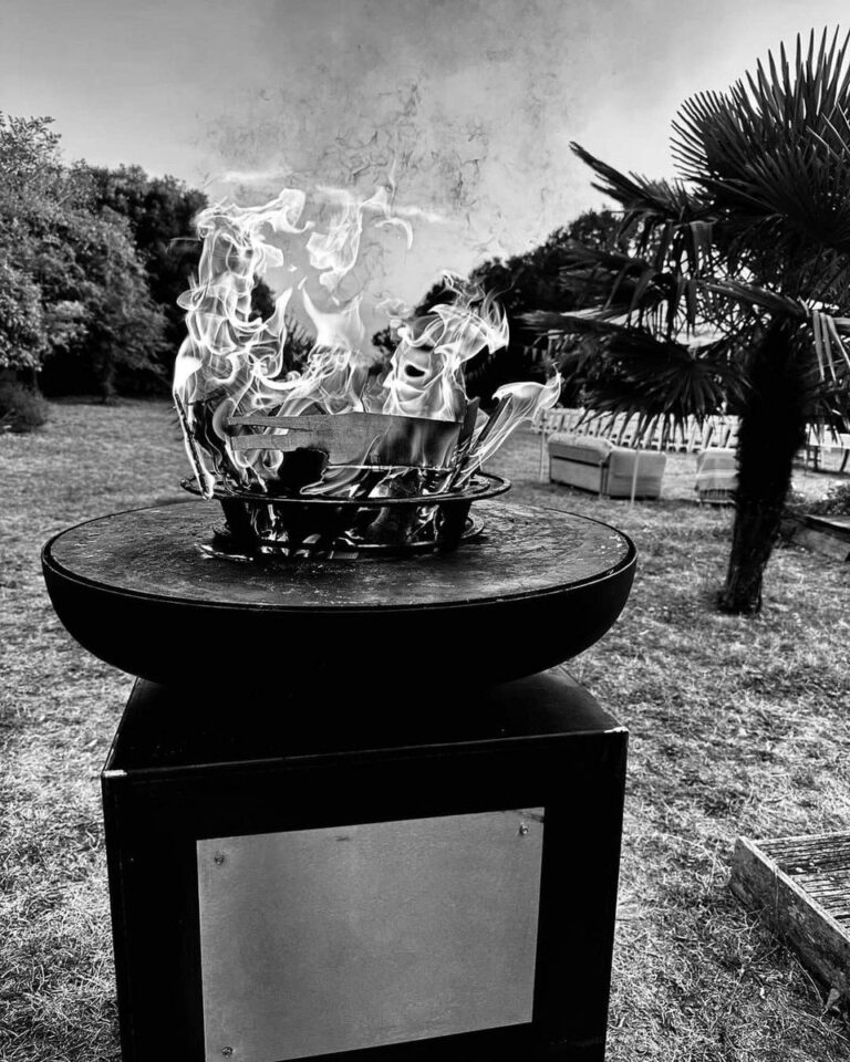 Braséro rond de 80 sur meuble noir, flammes dans le foyer, photo en noir et blanc