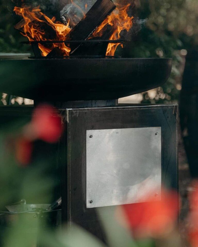 Plaque en inox sur le meuble d'un braséro, flammes au premier plan
