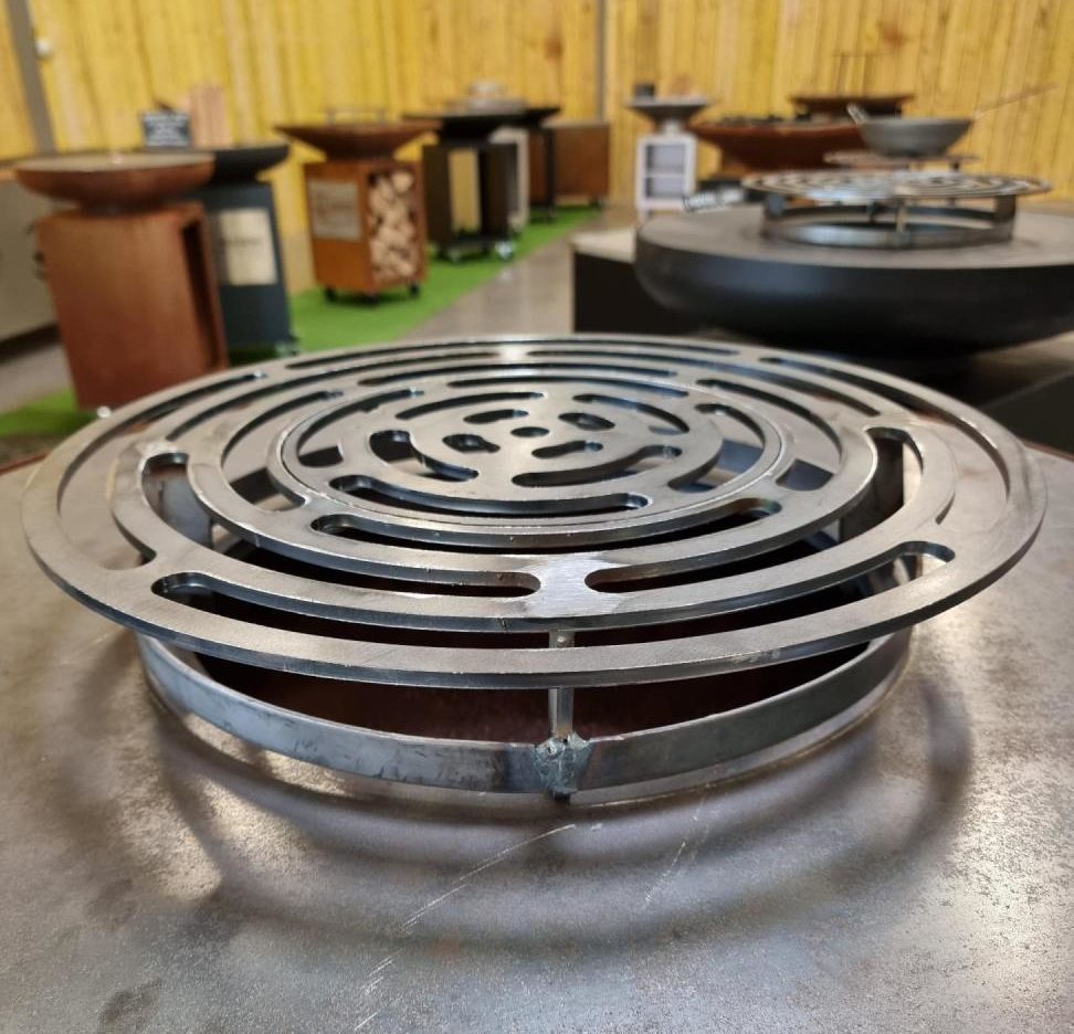 Grille ronde en acier posée sur la plaque de cuisson d'un braséro, vue de près