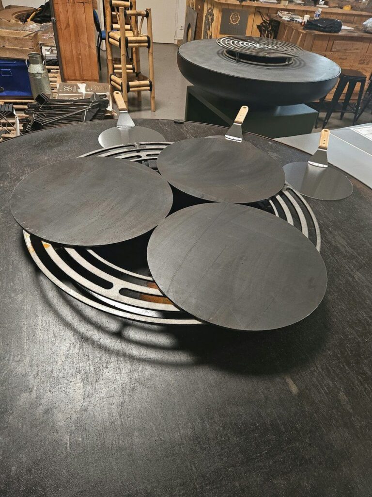 Trois crêpières en acier posées sur la grille d'un braséro de 150