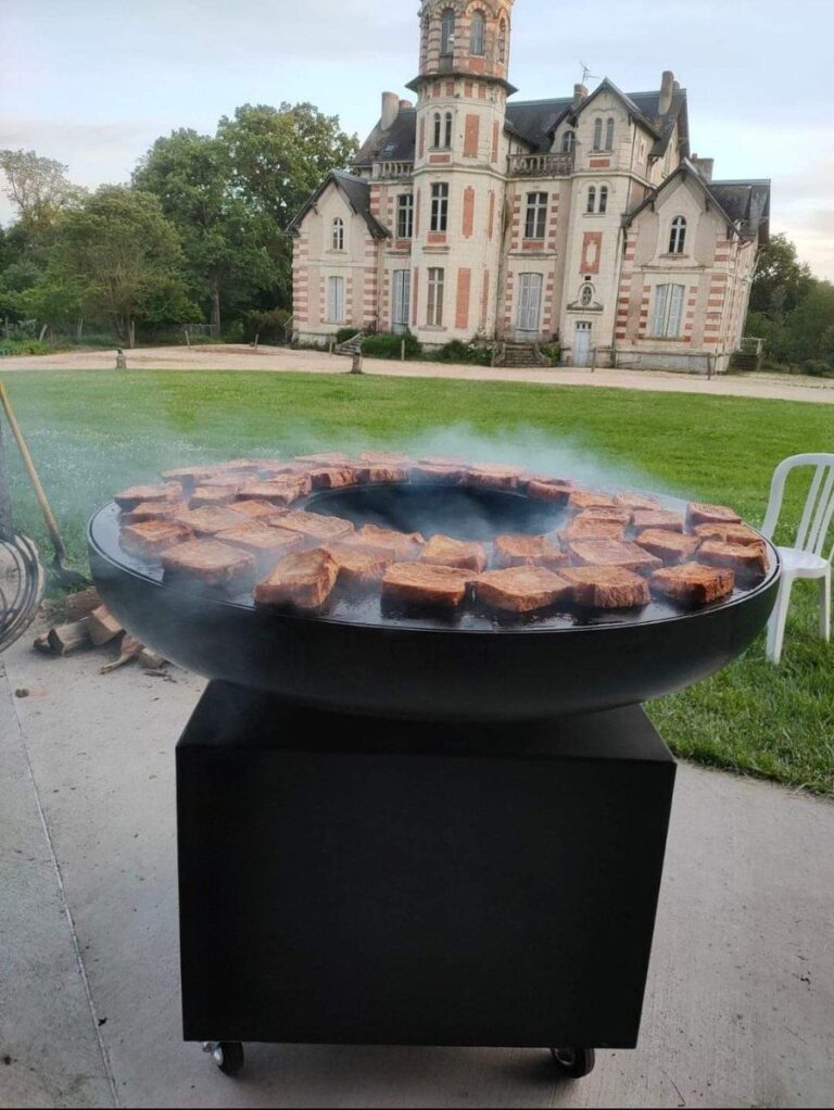 Braséro rond devant un château, tranches de viande en couronne sur la plancha