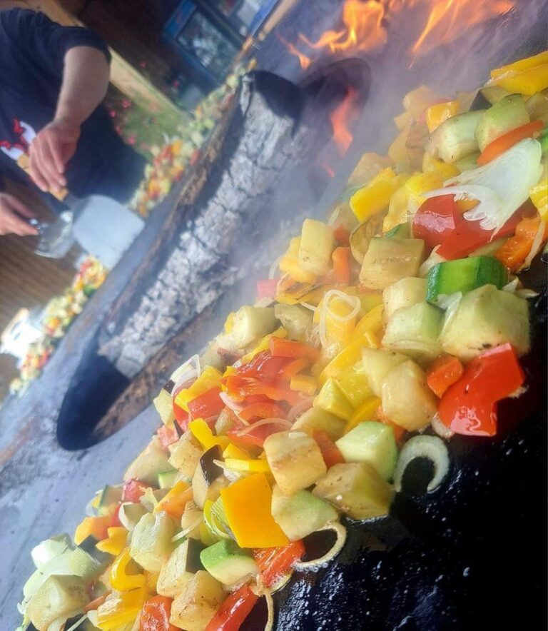 Dés de poivrons, courgettes et aubergines sautés sur la plancha, flammes à gauche