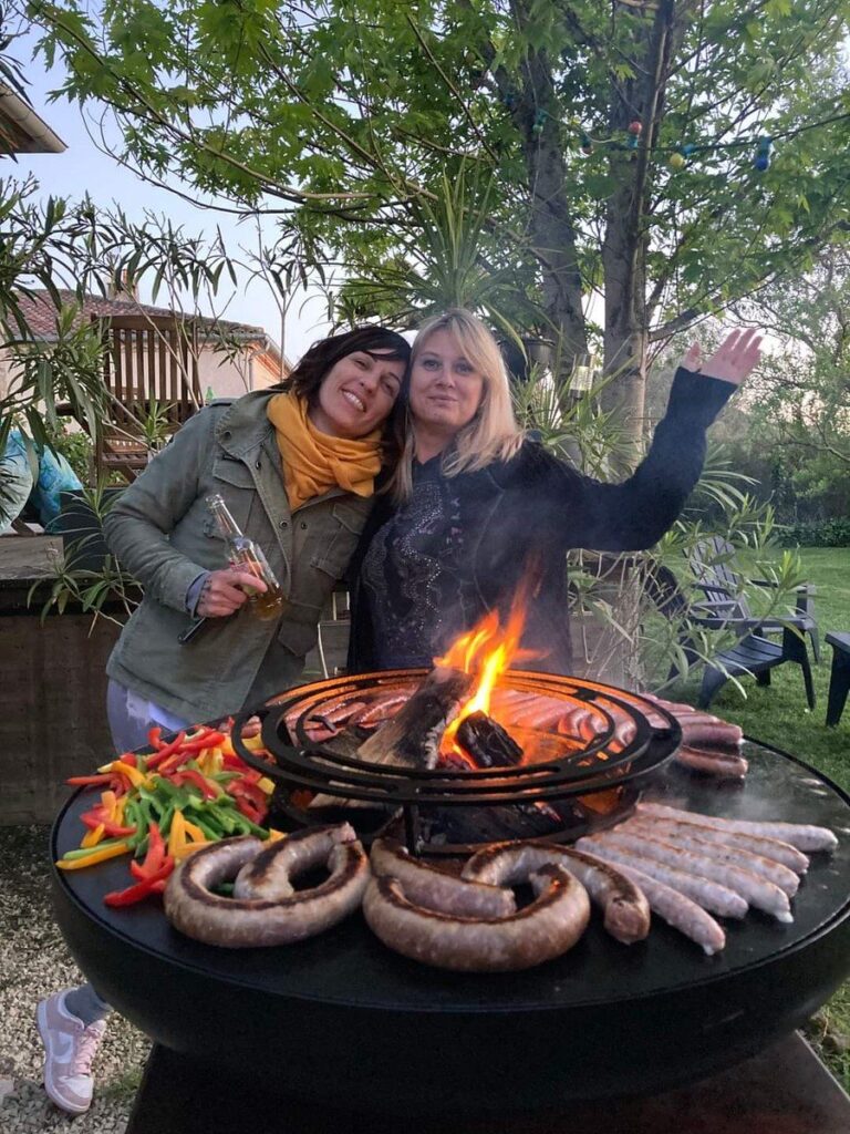 Deux amies autour d'un braséro garni de brochettes et de saucisses