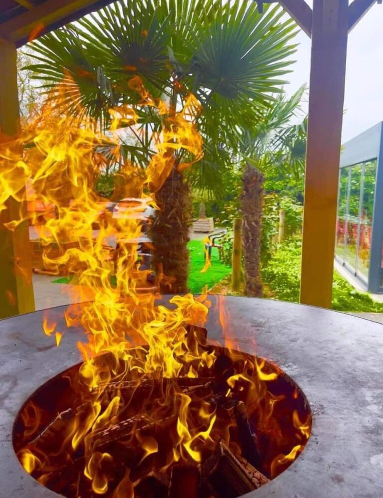 Grandes flammes dans le foyer d'un braséro, palmiers en arrière-plan