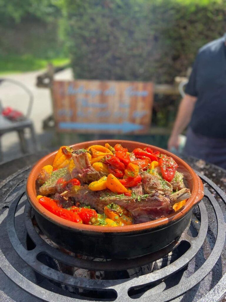 Poêle en terre cuite de poivrons posée sur la grille d'un braséro