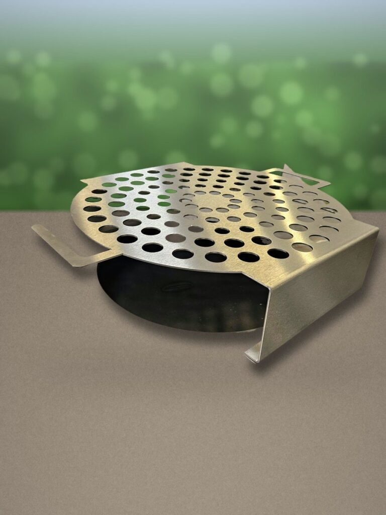 Grille à escargots en inox posée sur la plancha, showroom en arrière-plan