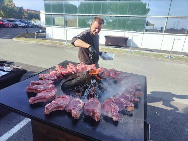 Cuisinier posant des côtes de bœuf en couronne autour du foyer d'un braséro carré de 80