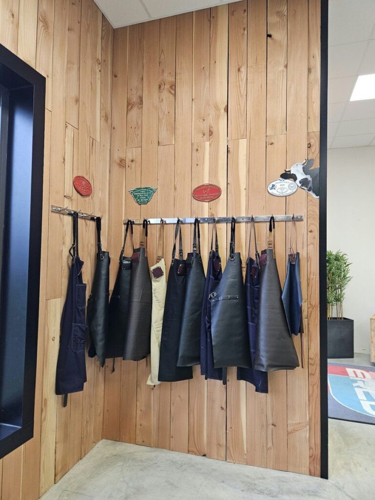 Tabliers en cuir noirs et marrons accrochés au mur du showroom